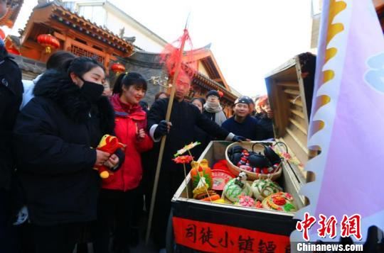 镖队走出几十米,就碰到对这种传统运镖方式十分好奇的游客,与镖师合影互动。互动过程中,游客们误以为是给游客送年货,导致这些年货被洗劫一空。 李庭耀 摄 镖队走出几十米,就碰到对这种传统运镖方式十分好奇的游客,与镖师合影互动。互动过程中,游客们误以为是给游客送年货,导致这些年货被洗劫一空。 李庭耀 摄