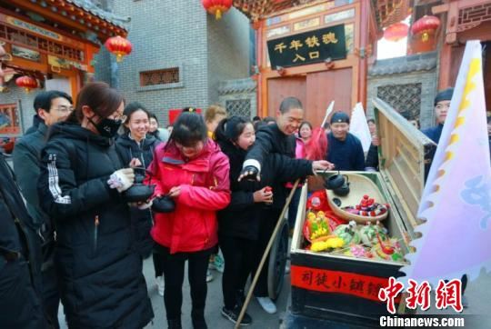 镖队走出几十米,就碰到对这种传统运镖方式十分好奇的游客,与镖师合影互动。互动过程中,游客们误以为是给游客送年货,导致这些年货被洗劫一空。 李庭耀 摄 镖队走出几十米,就碰到对这种传统运镖方式十分好奇的游客,与镖师合影互动。互动过程中,游客们误以为是给游客送年货,导致这些年货被洗劫一空。 李庭耀 摄