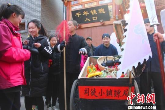 镖队走出几十米,就碰到对这种传统运镖方式十分好奇的游客,与镖师合影互动。互动过程中,游客们误以为是给游客送年货,导致这些年货被“洗劫一空”。 李庭耀 摄 镖队走出几十米,就碰到对这种传统运镖方式十分好奇的游客,与镖师合影互动。互动过程中,游客们误以为是给游客送年货,导致这些年货被“洗劫一空”。 李庭耀 摄