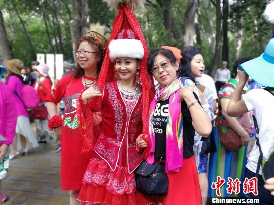 游客在阿勒泰市桦林公园与当地哈萨克族姑娘拍照。 王小军 摄